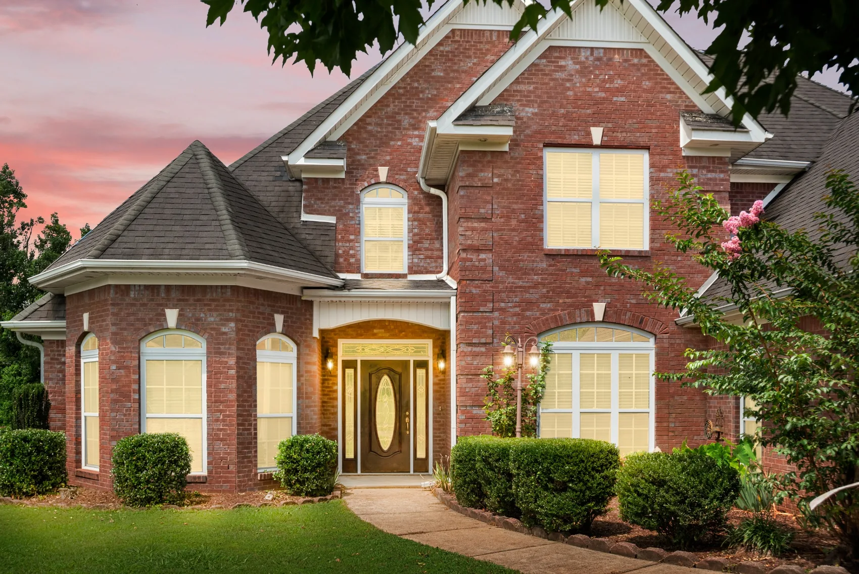 Twilight exterior of a brick home with warm illuminated windows