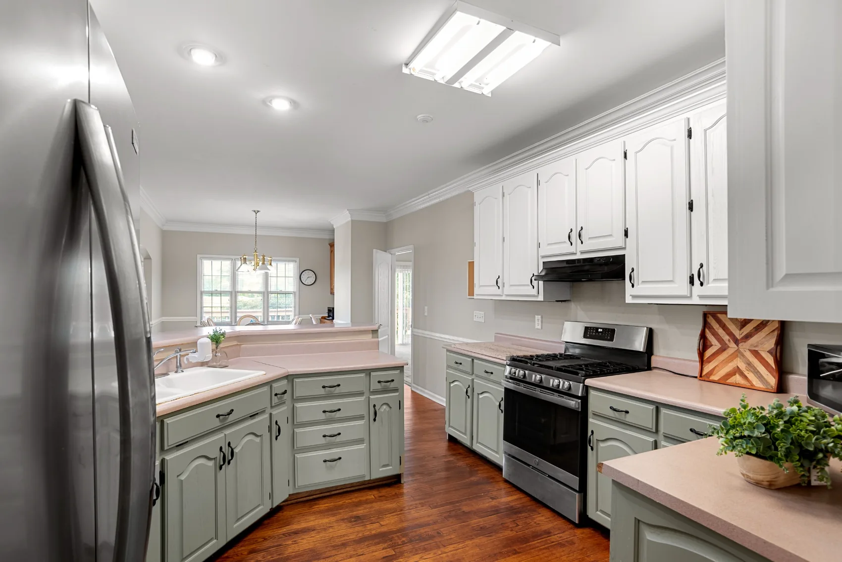 Kitchen with white cabinetry, pale green lower cabinets, and wood floors