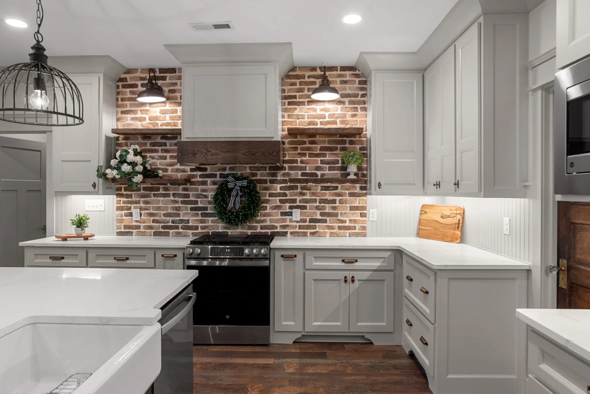 Close view of white kitchen cabinetry and brick range backsplash