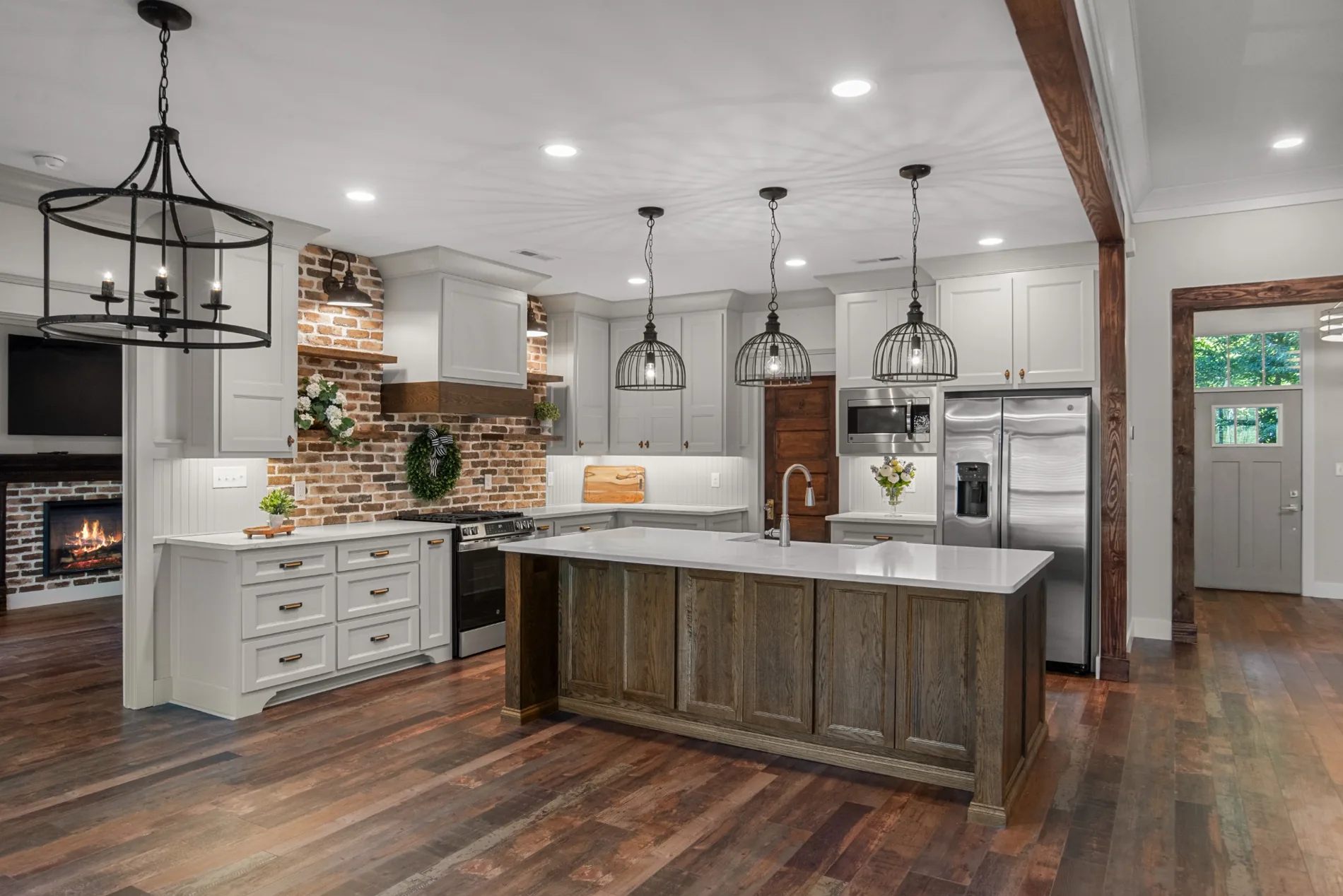 Spacious white kitchen with wood island, brick backsplash and pendant lighting